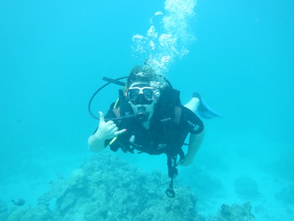 A woman poses for a picture while scuba diving.