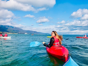 A woman in a red kayak smiles while on Lake Biwa in Japan.