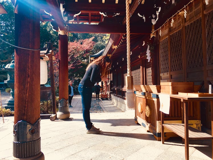 A woman bows in Kyoto, Japan on a sunny afternoon.