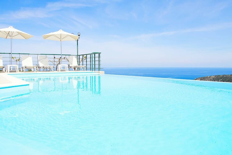 A blue infinity pool overlooks the ocean in this Airbnb rental in Greece. 