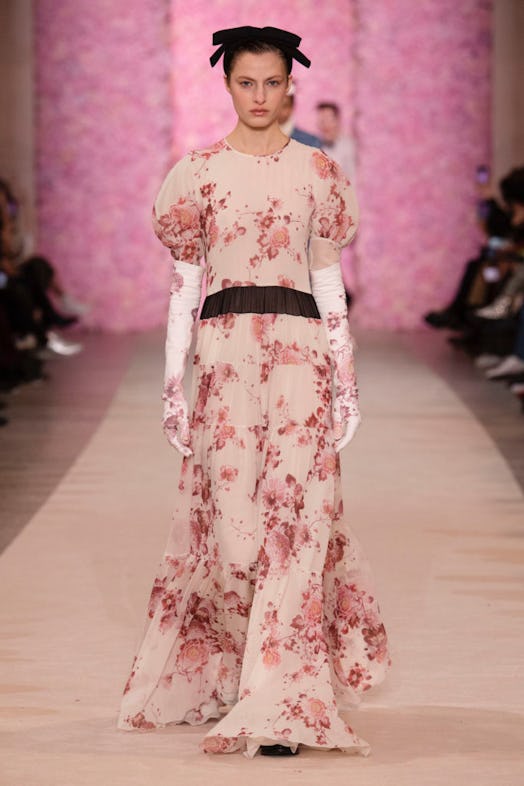 A model walking the runway in a diaphanous floral-print dress with puff sleeves and elbow-length glo...