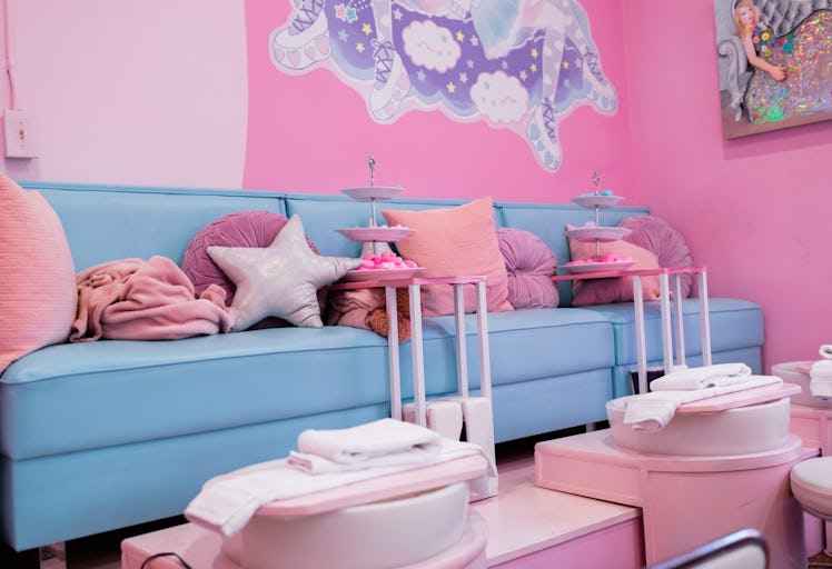 The interior of Cute Nail Studio in Austin, TX features a blue couch, pink walls, and lots of pink p...