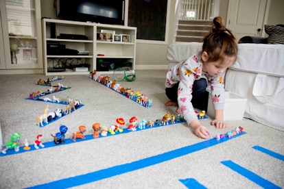 A girl lines up toy animals on some tape