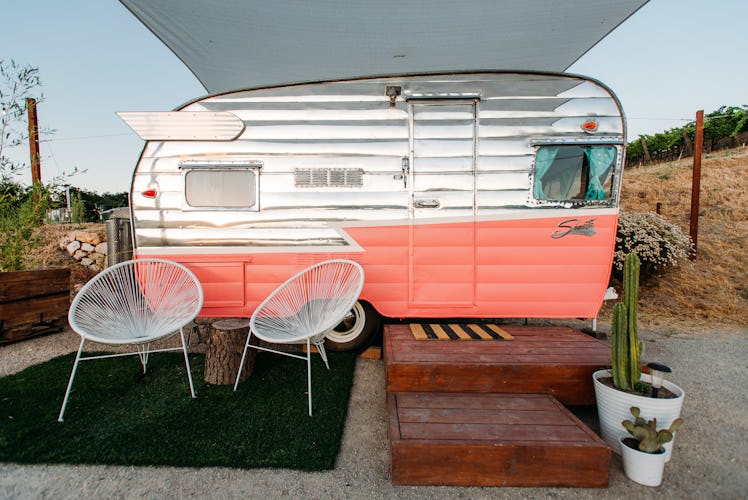 A pink and white vintage trailer at the Trailer Pond at Alta Colina Vineyard features outdoor seatin...