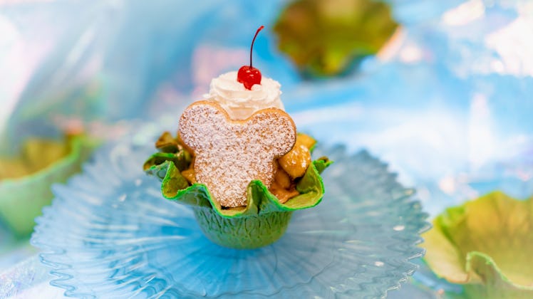 A Mickey Mouse-shaped sugar cookie sit on top of an ice cream sundae in a green waffle bowl at Disne...