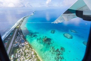 Tuvalu under the wing of the airplane. Aerial view of Funafuti atoll and airstrip of international a...