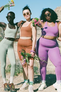 Three girls posing in green, orange, and purple tops and leggings