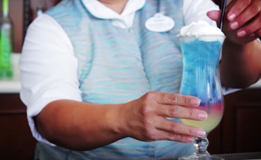 A bartender puts a straw into a colorful Disney drink.