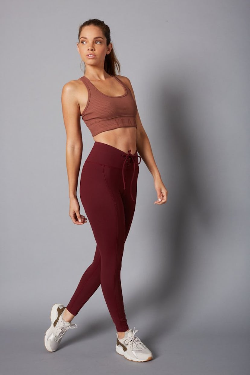 A brunette girl posing in a burgundy combination of a top and leggings
