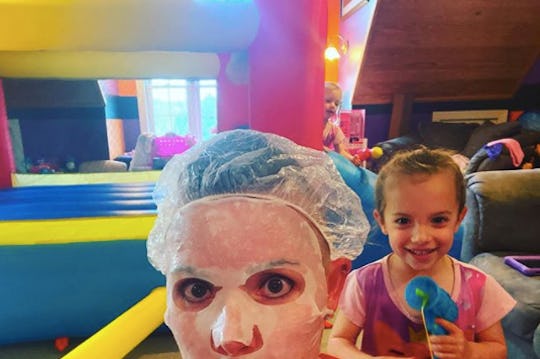 A mother wearing a face mask in front of a bouncy castle