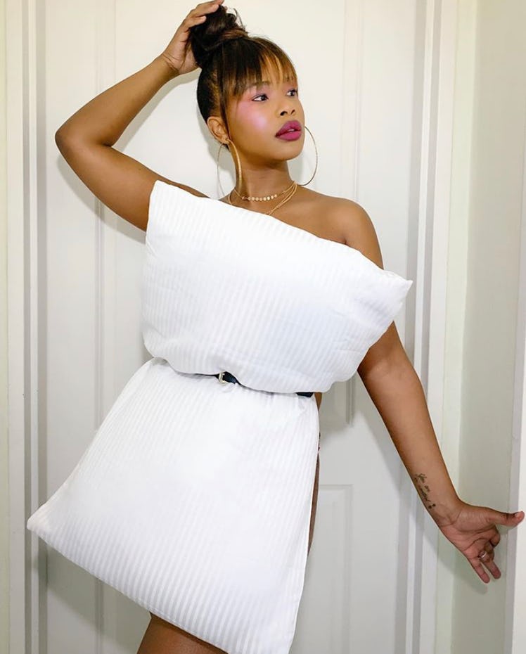 A woman poses with a pillow outfit in her room.