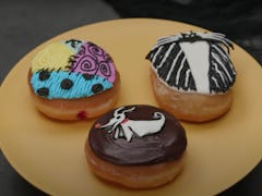 Three doughnuts decorated to look like characters from 'The Nightmare Before Christmas' are placed o...