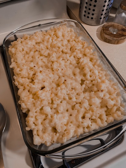 A glass casserole dish of homemade mac and cheese sits on a stovetop.