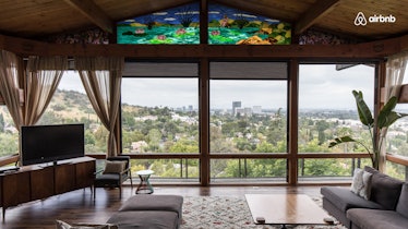 A vintage home in the Hollywood Hills has a large living room with windows all around. 