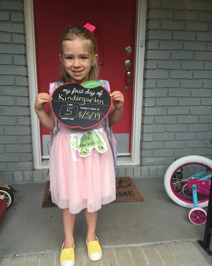 The author's daughter holds a first day of kindergarten photo