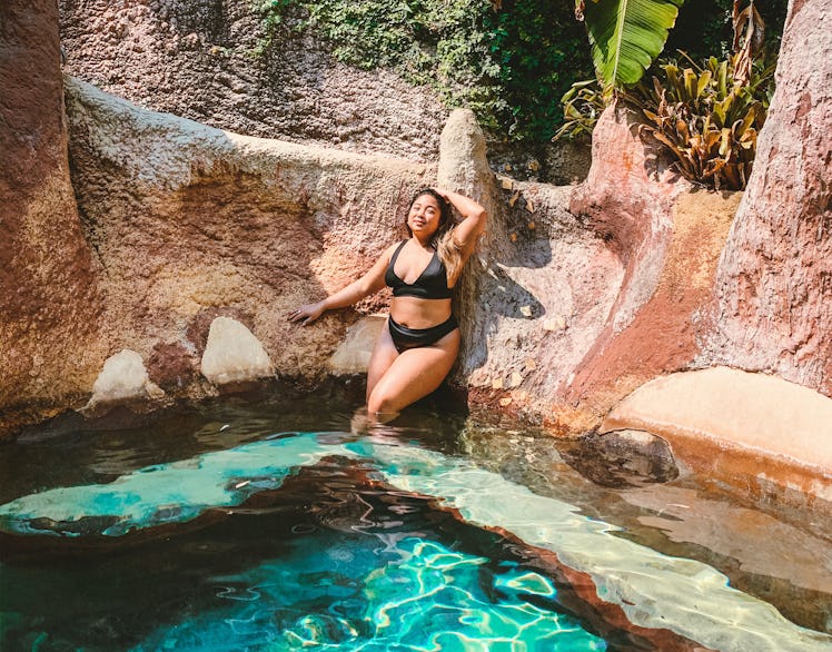 A woman in a black bikini poses in a hot spring in New Zealand.