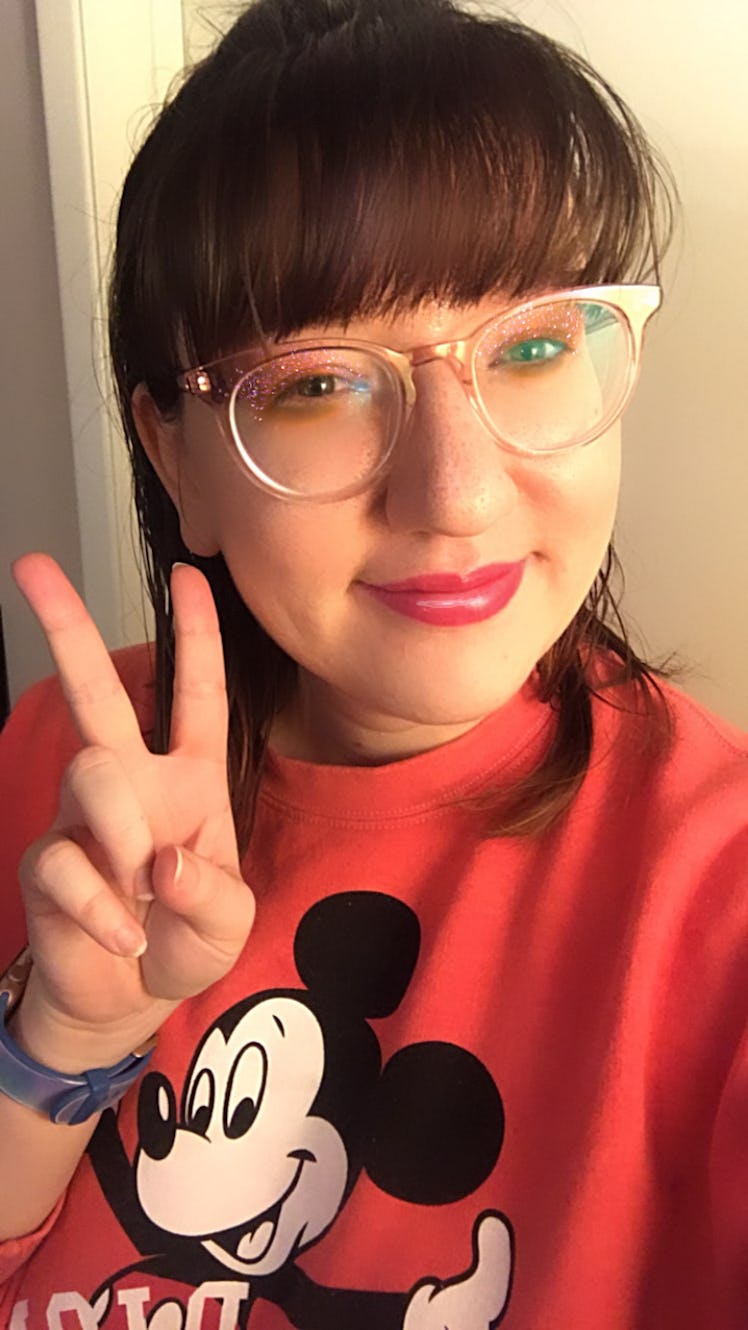 A woman gives a peace sign while wearing a Mickey Mouse sweater, and wearing glittery eye makeup fro...