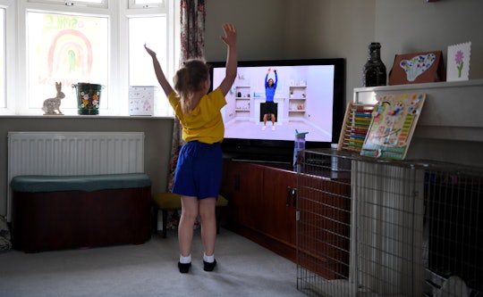 A girl exercises along with her teacher through a screen