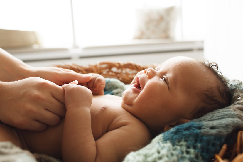 newborn baby lying on back, smiling at mom in a list of best baby name generators 