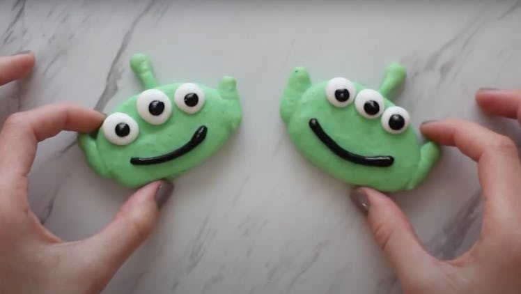 A woman's hands hold onto two Alien-themed macarons from 'Toy Story.'