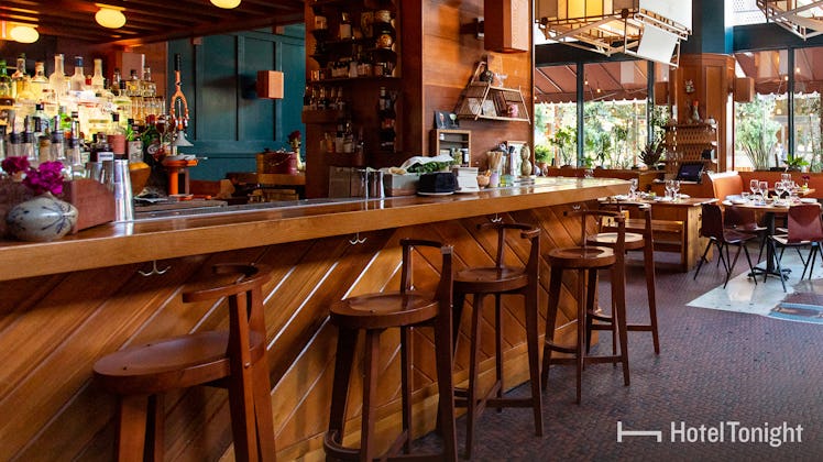 A restaurant bar in Los Angeles, California features cozy barstools and a moody atmosphere.