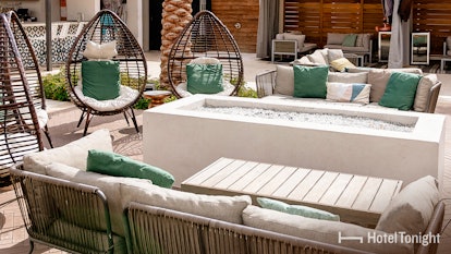 An outdoor patio of a hotel features white and teal furniture, and a lighthearted atmosphere.