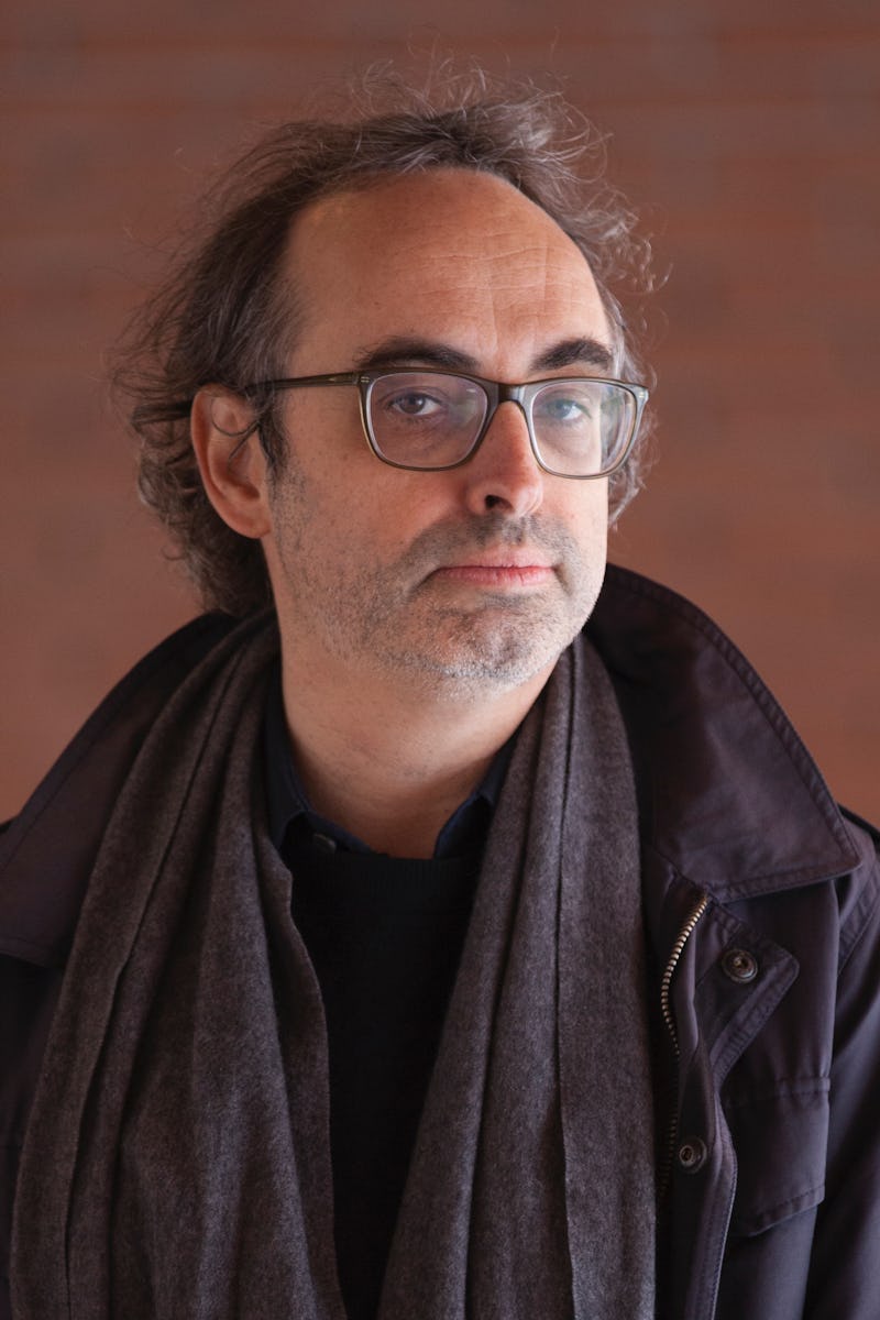 Gary Shteyngart in a black shit, black jacket, and black scarf also wearing glasses