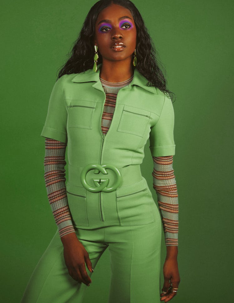 Zuri Tibby is wearing a green Gucci jumpsuit and belt, while she poses for the photograph in the gre...