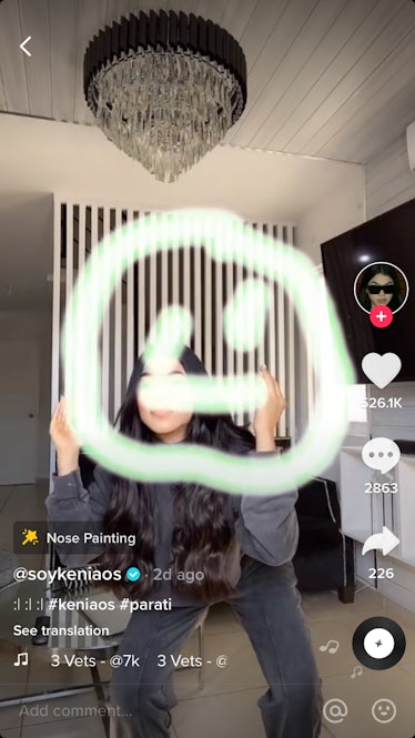 A woman draws a smiley face with her nose in her living room while doing a TikTok challenge.