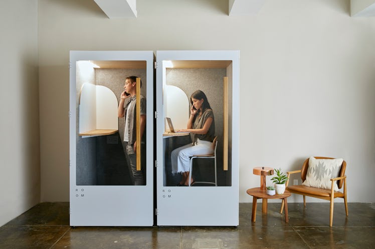 A man and a woman in two office phone booths