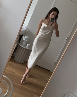 Lauren Caruso taking a photo of herself in the mirror while wearing a white silk dress