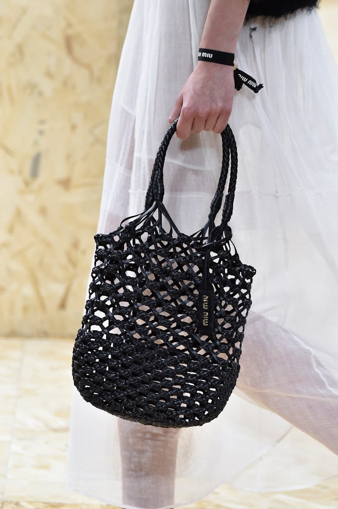 The closeup of a woman carrying a black woven bag