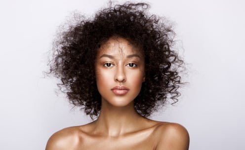 Young lady with curly hair and cared skin posing for a photo