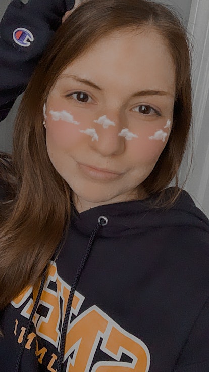 A young woman in a sweatshirt poses with an Instagram filter applied to her face.