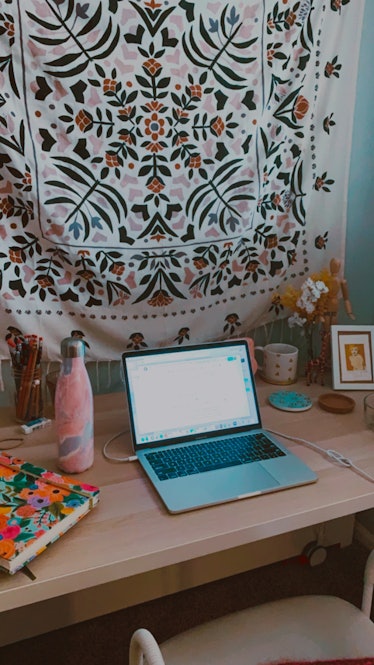 An office space is decked out with a tapestry, floral planner, and colorful water bottle.