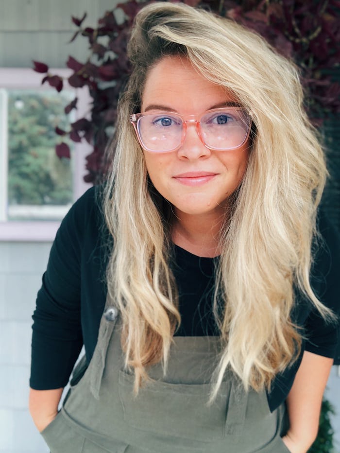 Kate Baer posing in a grey overall and black shirt