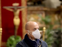 A Vatican employee wearing a protective mask attends Pope Francis' Palm Sunday Mass in an empty Vati...