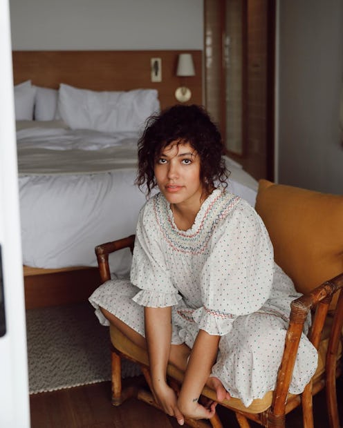 A woman in a white frilled puff-sleeved lingerie dress working from bed