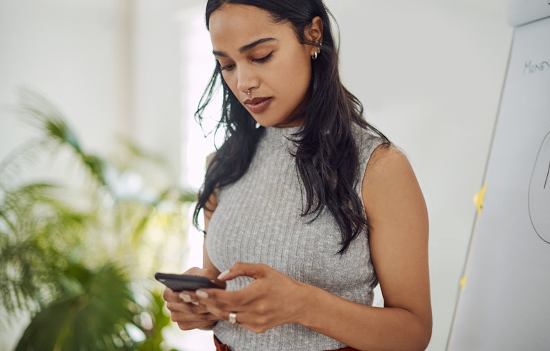 A young black-haired lady using a dating app on her phone