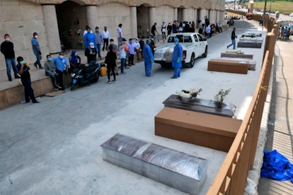 People wait next to coffins and cardboard boxes to bury their loved ones outside a cemetery in Guaya...