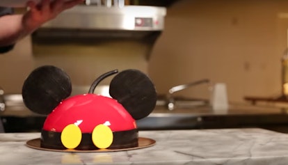 A Mickey Mouse-shaped dome cake sits on the counter in a kitchen. 