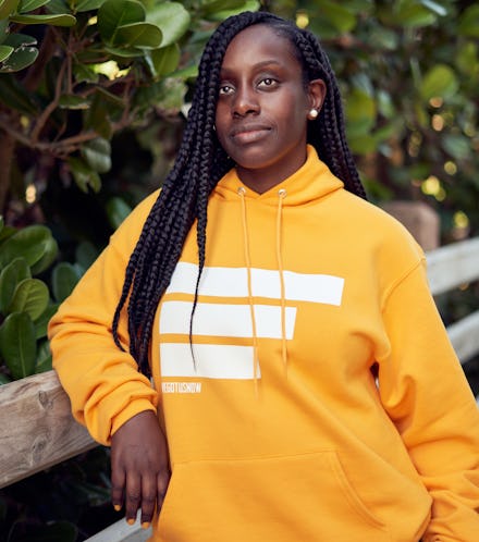 A woman with dreadlock hairstyle posing for a photo in a yellow hoodie