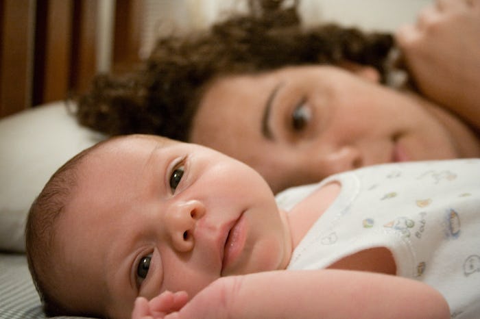 a mother lies next to her newborn