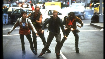 A group of four men rollerblading down a street