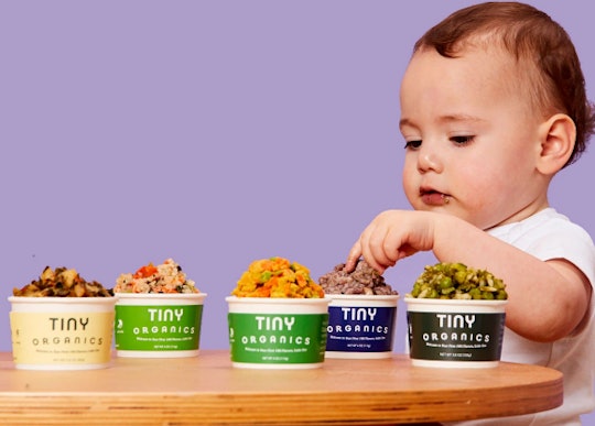 a baby looking at several containers of tiny organics baby food