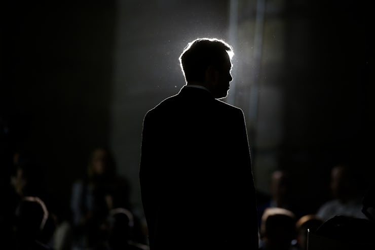 Elon Musk giving a speech in front of an audience while standing
