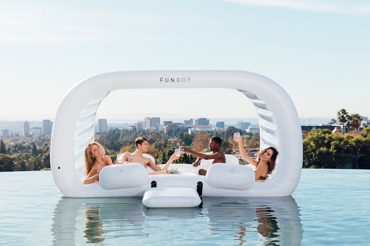 A group of friends hangs out on FUNBOY's Giant Dayclub pool float while in an infinity pool overlook...