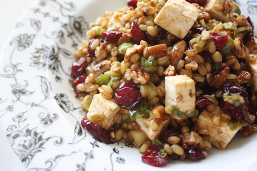 Plate with a pile of wheat berry salad featuring cranberries, pecans, green onions, and feta cheese 