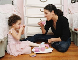 A mom has a tea party with her daughter on the floor