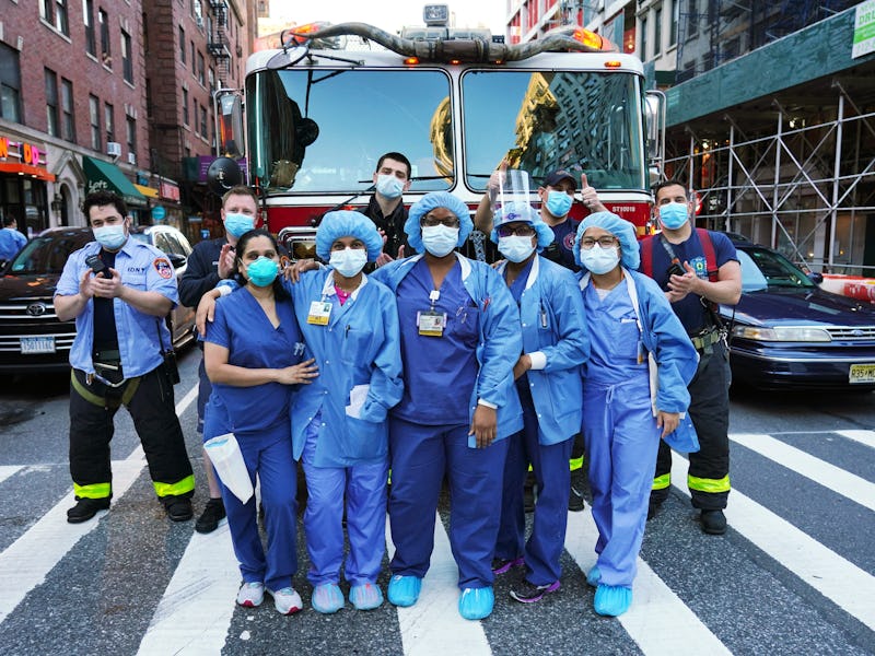 Medical workers from Lenox Hill Hospital come outside and pose with members of the FDNY while peopl...
